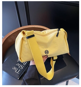 Detailed close-up of yellow nylon crossbody bag with metal M logo and wide strap