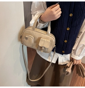 Detailed close-up of a beige faux leather satchel bag with stylish multi-pocket design