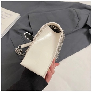 Side view detail of white minimalist square crossbody bag with silver chain strap
