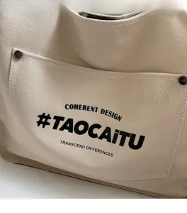 Detailed macro view of beige canvas tote bag showing the front pocket and metal button accents