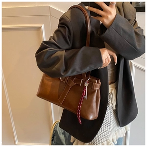 Detailed view of a retro dark brown leather underarm bag with belt buckle and key charm