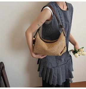 Détail du sac à bandoulière en paille beige avec sangle en cuir marron sur le modèle