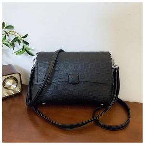 Detail view of black embossed geometric texture and protective studs on shoulder bag base