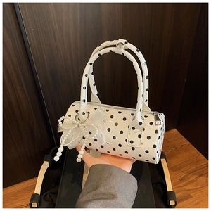 Vue détaillée du sac cylindrique blanc à pois avec nœud en perles et zip métallique