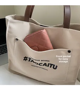 Detail of canvas tote bag front pocket showing storage for a pink wallet in office setting