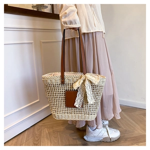 Detail of woven straw tote with leather straps and white lace bow for summer beach style