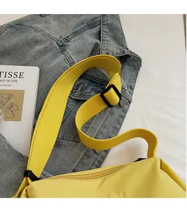 Detailed view of yellow nylon crossbody bag with adjustable strap over blue denim jacket