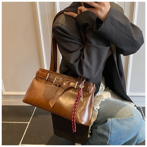 Detail of vintage brown shoulder bag with metal buckle and red woven key ornament
