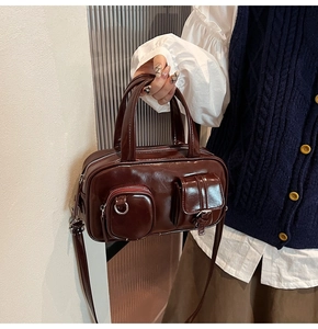 Macro detail of dark red retro Boston bag with functional pockets and silver hardware