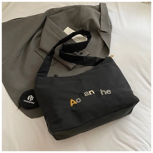 Vue détaillée du sac cabas en nylon noir avec broderie et mini pochette assortie