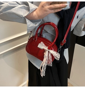 Detail der roten Mini-Tasche mit weißer Spitzenschleife und glänzender Oberfläche
