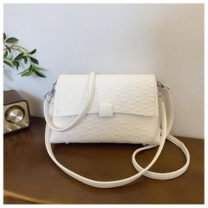 Detail of white rectangle shoulder bag with geometric embossed pattern on a wooden table