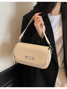Petit sac bandoulière beige avec rabat tissé et plaque en métal porté par un mannequin
