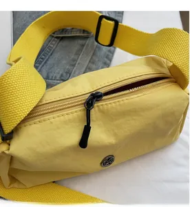 Close-up of bright yellow nylon crossbody bag featuring smooth black zipper and metal logo
