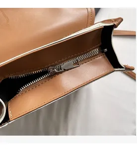 Gros plan sur la fermeture éclair en métal et le cuir grainé marron du sac à dos