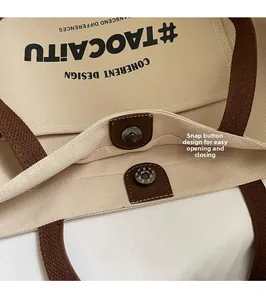 Close-up of the secure magnetic snap closure on a beige canvas tote bag with brown trim
