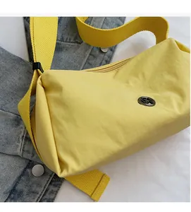 Close-up of bright yellow nylon crossbody bag featuring soft fabric and round metal logo