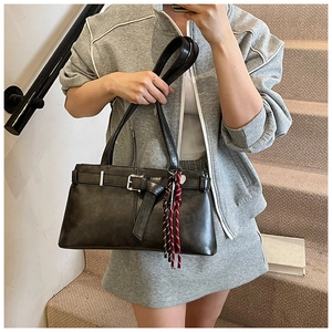 Detail of dark gray leather shoulder bag with buckle and red rope pendant on stairs