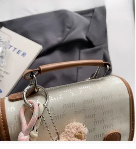 Détail du sac à dos monogramme crème avec poignée en cuir brun et breloque ours