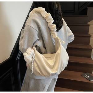 Detail of cream cloud bag with ruched bubble strap and cute plush cat keychain