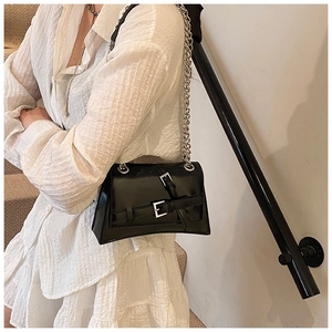Close-up of black crossbody bag with silver hardware and chunky chain on model