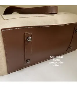 Detail of canvas tote base with brown leather trim and metal protective bottom rivets