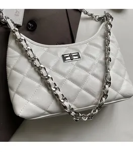 Detail einer weiß gesteppten Ledertasche mit silbernem Metalldrehverschluss und Kette