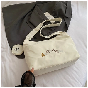 Détail du sac fourre-tout crème avec broderie AORANSHE et petit porte-monnaie rond