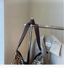 Detail of leopard print tote bag showing durable brown webbing strap and metal ring hardware