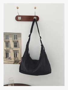 Detail der schwarzen karierten Hobo-Tasche mit verstellbarem Gurt an einem Wandhaken