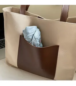Detail of the back slip pocket on a cream canvas tote bag with brown leather accents