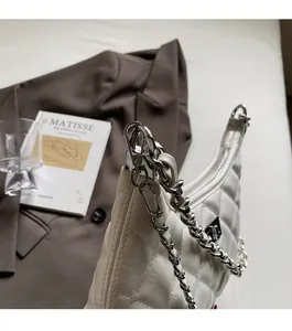 Details der weißen gesteppten Ledertasche mit Silberkette und Dreiecks-Logo-Plakette