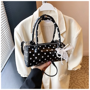 Gros plan du sac cylindre à pois rétro avec breloque perle et nœud en dentelle