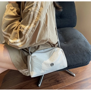 Detail of off-white quilted nylon crossbody bag with zipper and small metal logo