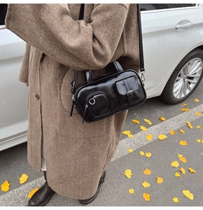 Detail of vintage black gloss crossbody bag styled with a warm brown wool coat in autumn