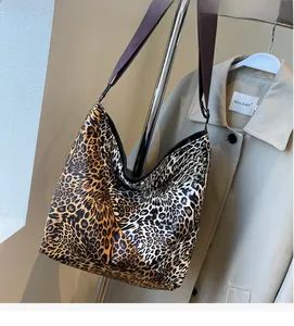 Detailed side view of a large leopard print hobo bag with wide coffee-colored shoulder strap