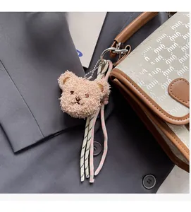 Détail d'un pendentif ours en peluche avec pompon tissé et chaîne sur un sac à dos