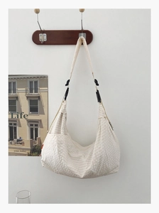 Detail der cremefarbenen Hobo-Tasche mit Waffelstruktur und verstellbarer schwarzer Schnalle