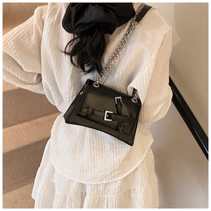 Detail of minimalist black faux leather shoulder bag with silver chain on model