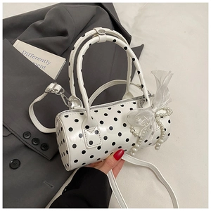 Close-up of white polka dot cylinder handbag with tulle bow and pearl charm