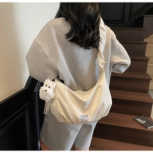 Detail of off-white dumpling bag with pleated shoulder strap and plush puppy charm