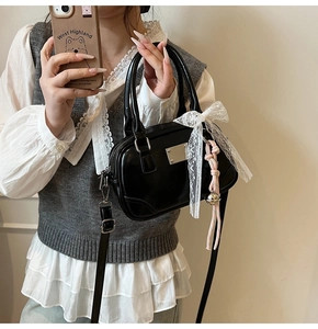 Spiegel-Selfie der schwarzen Lackleder-Bostontasche mit weißer Spitzenschleife und Silberdekor
