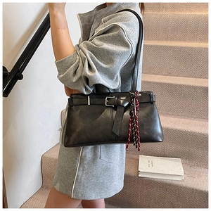 Detail of black tote bag with strap buckle and red woven rope on a model