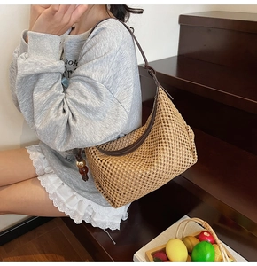 Détail du sac hobo en paille tressée avec bandoulière en cuir et pendentif ambre décoratif