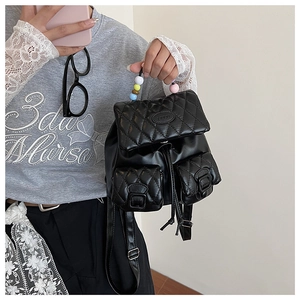 Detail view of black quilted faux leather bag with colorful beaded handle and pockets