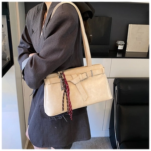 Detail of cream leather shoulder bag with decorative buckle and striped silk scarf tassel