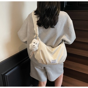 Detail of cream puffy shoulder bag featuring a fashion tag and cute plush dog pendant