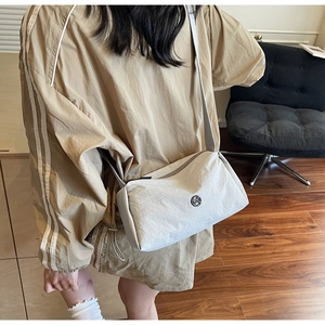 Macro shot of minimalist cream crossbody bag with nylon texture and metal logo detail