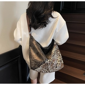 Detail of a large leopard print hobo bag with a wide brown strap worn by a model