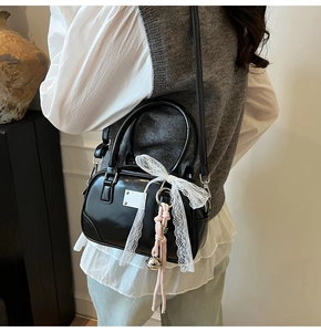 Detail der schwarzen Bowling-Tasche mit Spitzenschleife und Anhänger an einem Model